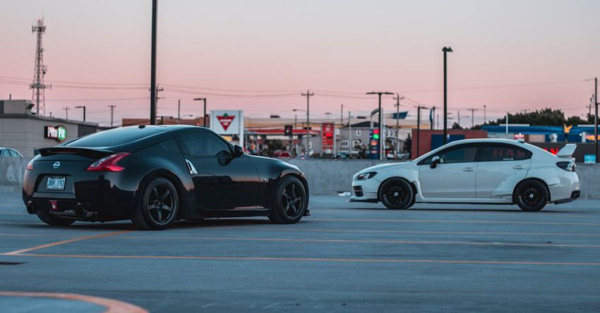 Mustang Engine Tuning - Stylish black and white sports cars parked on asphalt parking area in outskirts against cloudless sunset sky