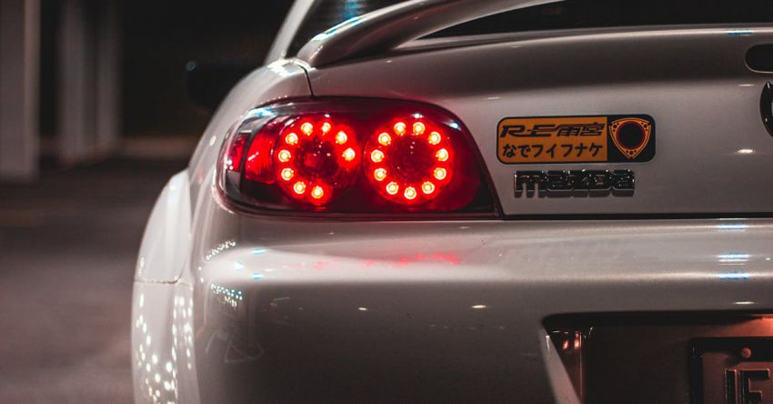 Mustang Engine Tuning - Trunk of shiny trendy modern car with glowing back lights in parking lot at night